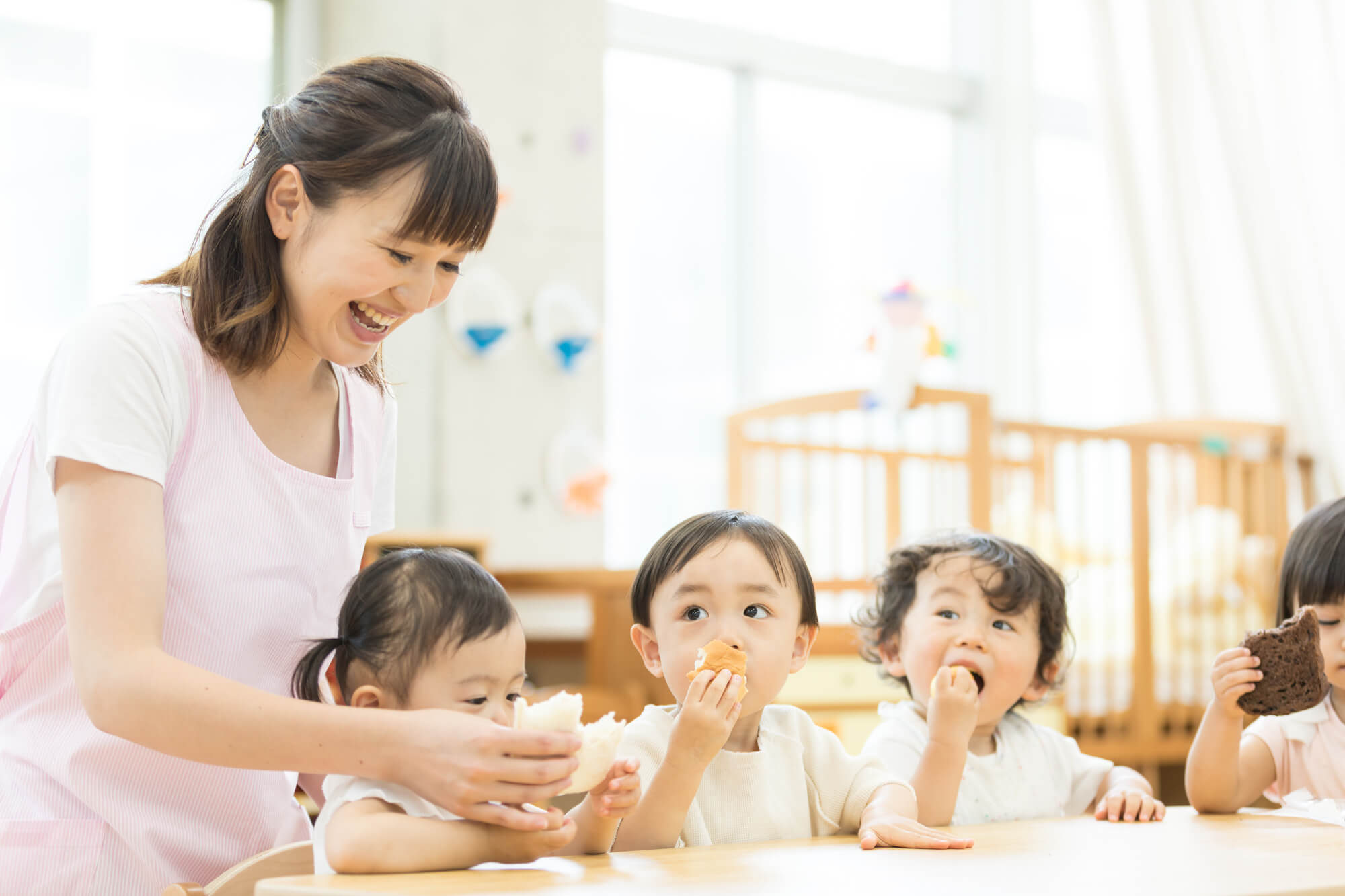 保育士とおやつを食べる子ども